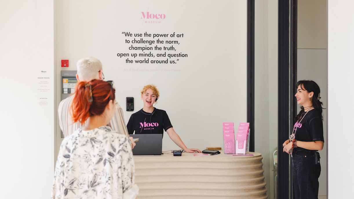 Reception area of Moco Museum London with staff assisting visitors.