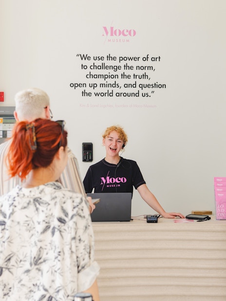 Reception area of Moco Museum London with staff assisting visitors.