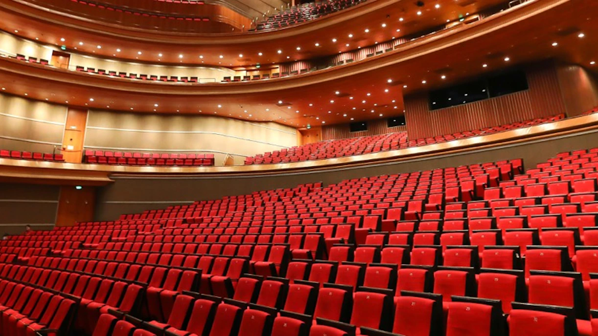 Red seats in a large, empty theatre auditorium with multiple balconies.