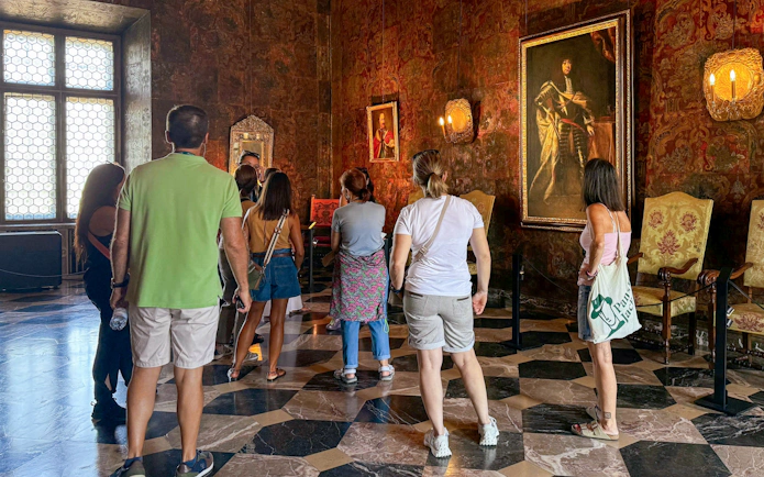 Visitors observing paintings in the State Rooms of Wawel Royal Castle, Krakow.