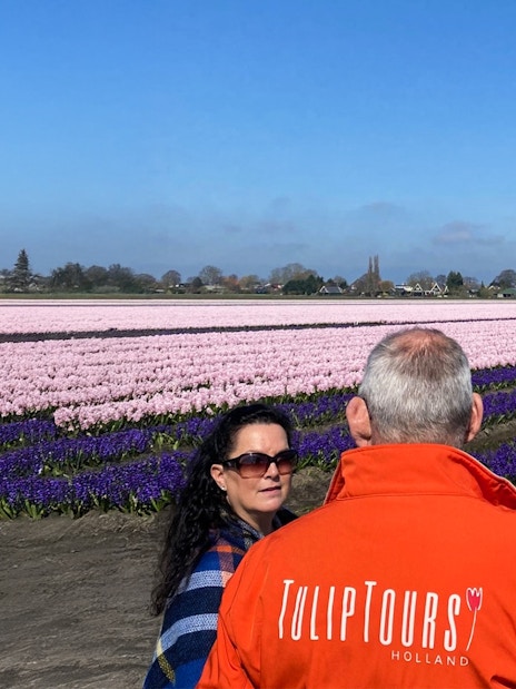 Tour guide leading a small group at colorful tulip fields in Holland.