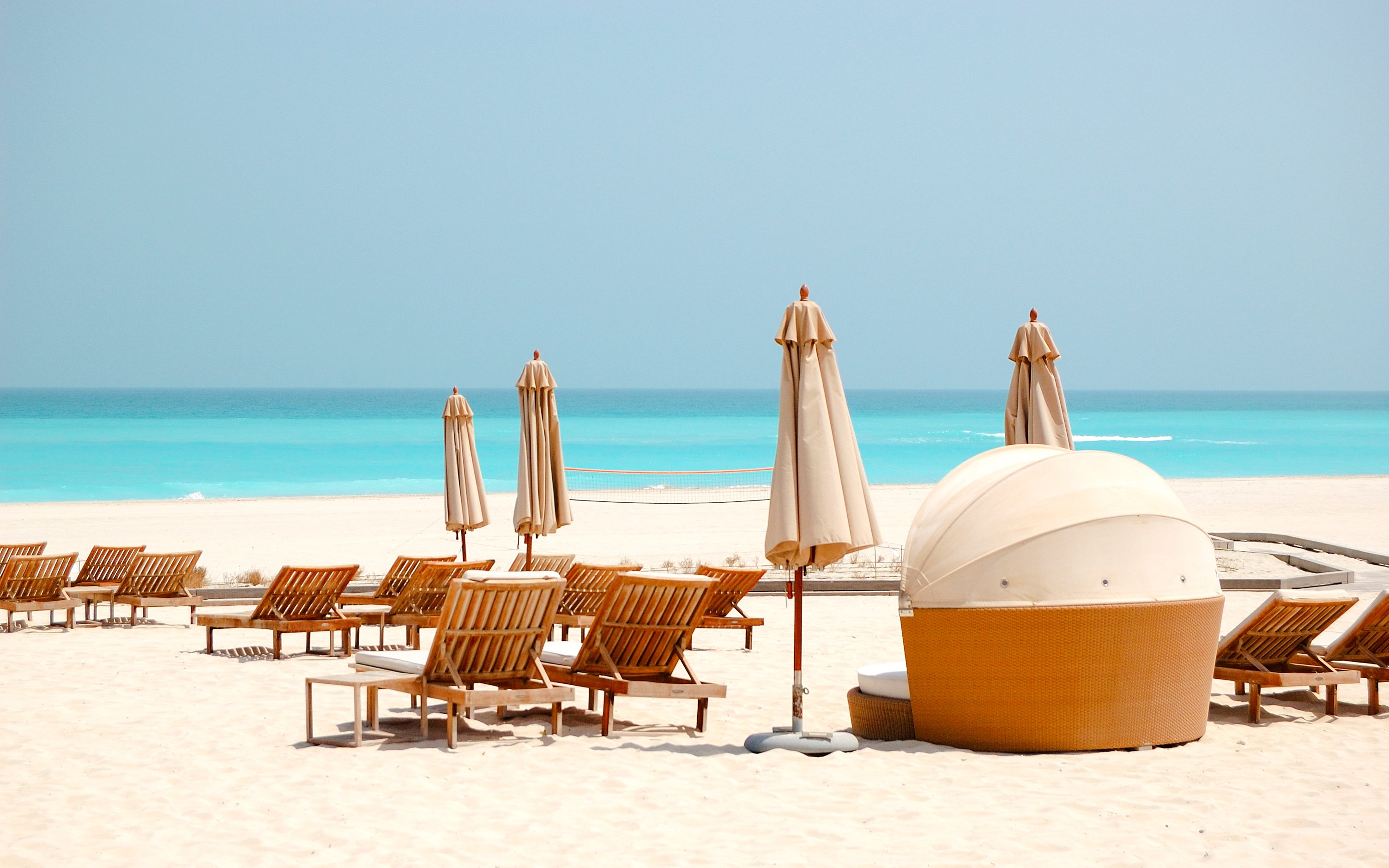 Beach chairs and umbrellas on Saadiyat Island, Abu Dhabi, overlooking turquoise sea.