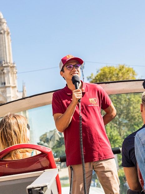 Tour guide speaking on Big Bus near Notre-Dame Cathedral, Paris.