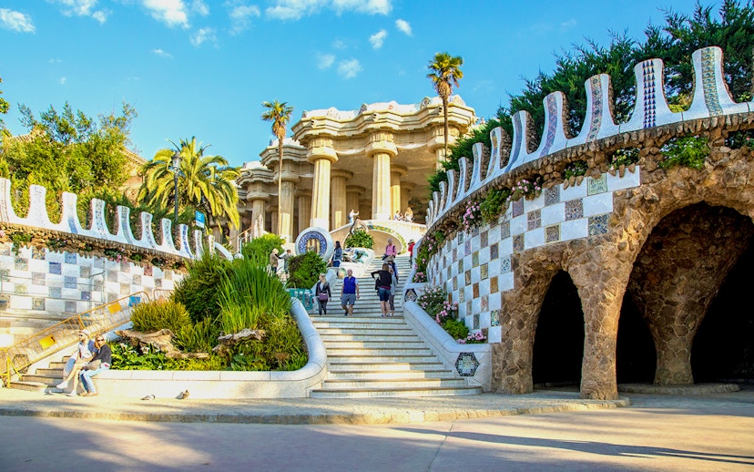 Park Güell entrance with mosaic walls and visitors in Barcelona, Spain.
