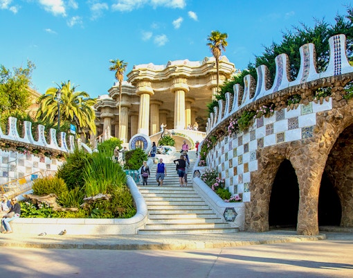 Park Güell entrance with mosaic walls and visitors in Barcelona, Spain.