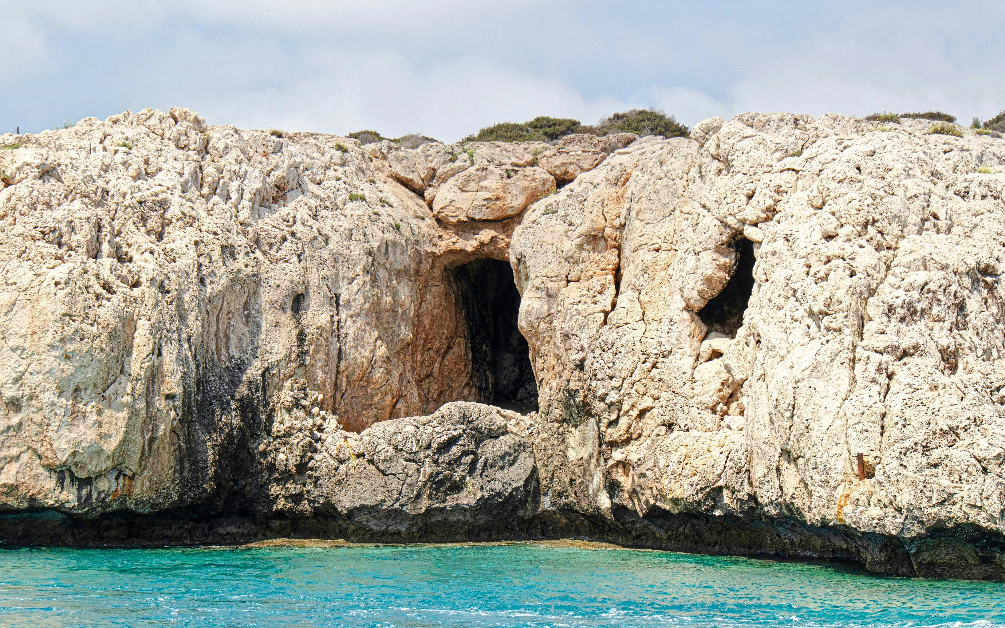 Pirates Cave at Cape Greco, rocky cliffs above turquoise Mediterranean waters, Protaras, Cyprus.