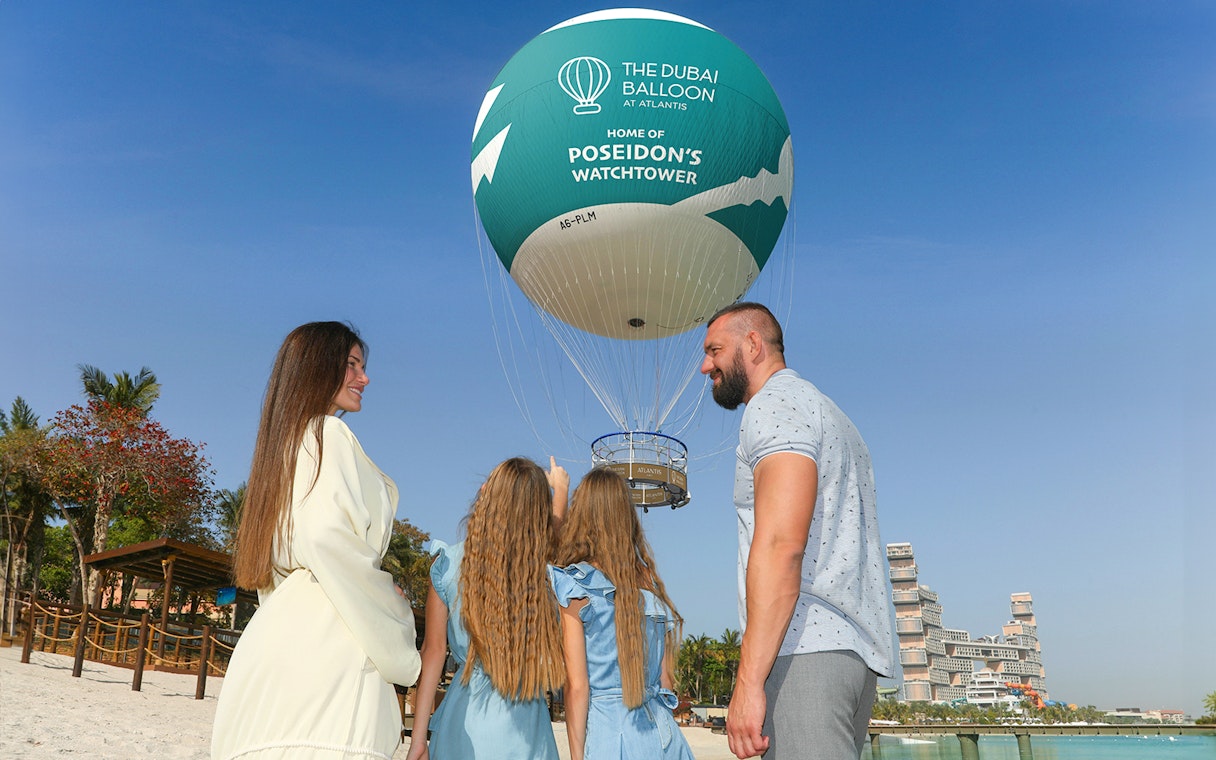 Family observing The Dubai Balloon at Atlantis with resort in background.