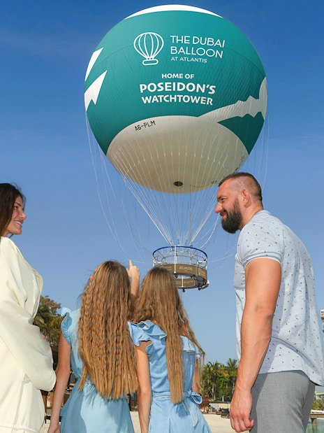 Family observing The Dubai Balloon at Atlantis with resort in background.
