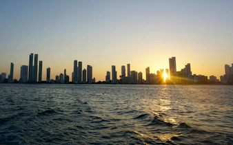 Cartagena skyline at sunset with sun setting behind high-rise buildings.