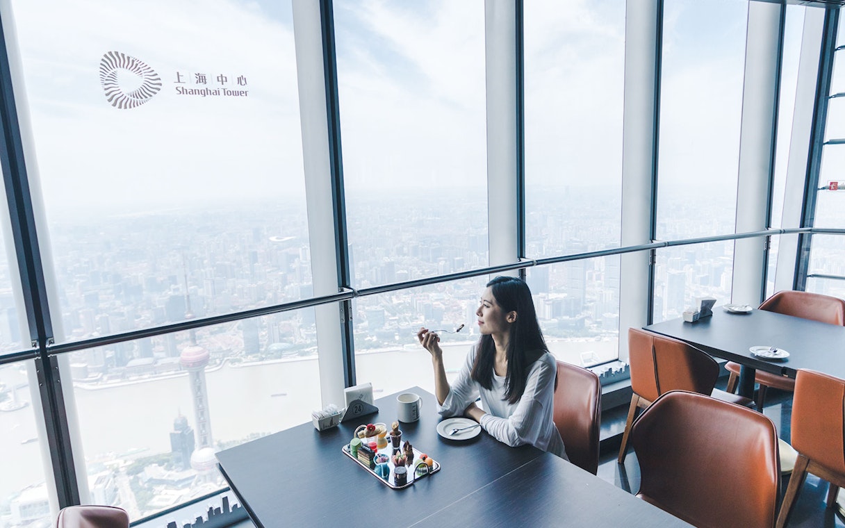 Woman enjoying desserts with a view of Shanghai from Shanghai Tower.