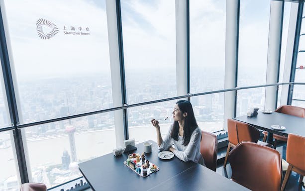 Woman enjoying desserts with a view of Shanghai from Shanghai Tower.