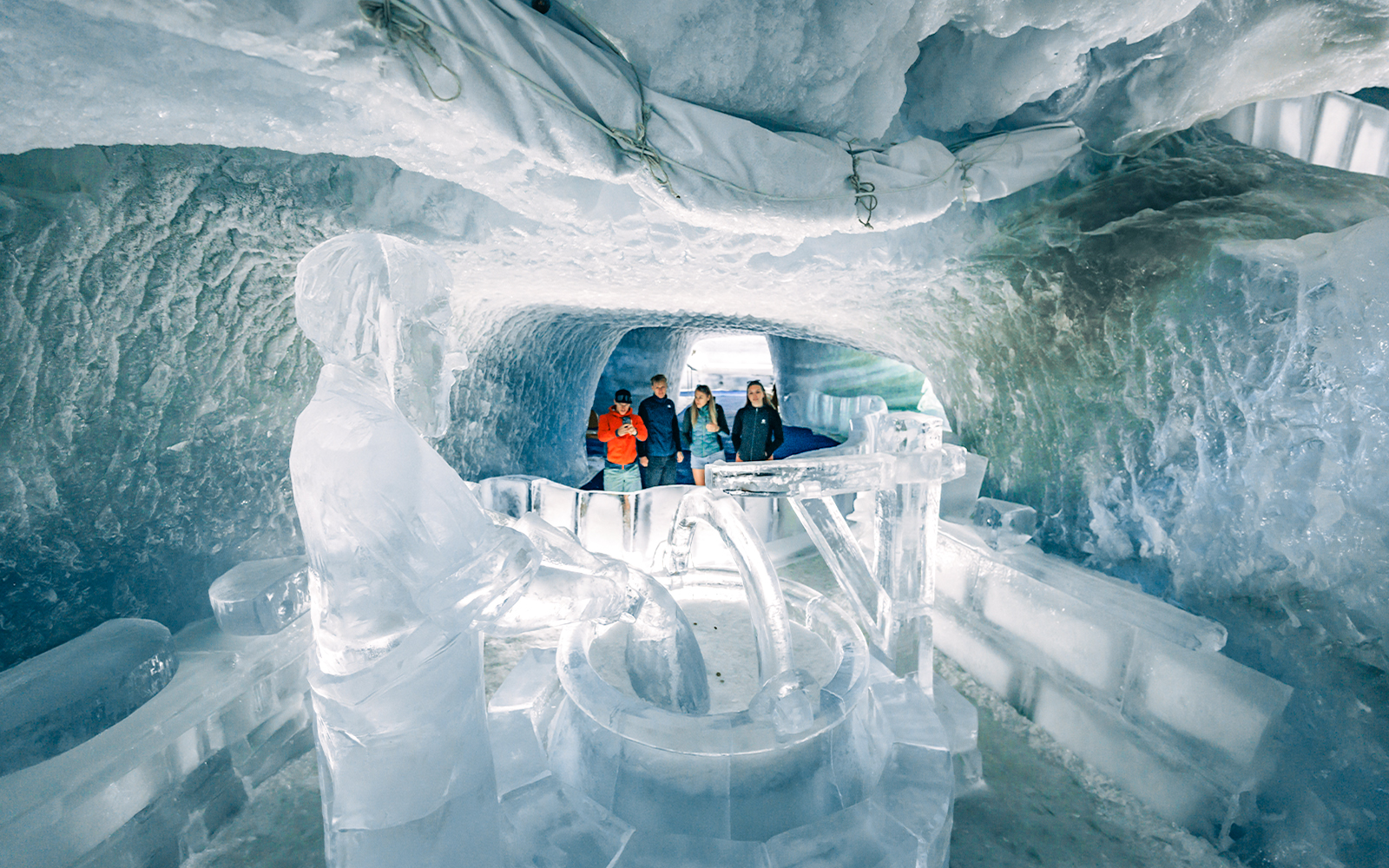 Tourists exploring ice sculptures inside Glacier Palace at Matterhorn Glacier.