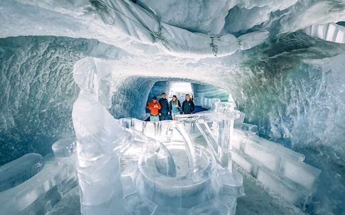 Tourists exploring ice sculptures inside Glacier Palace at Matterhorn Glacier.