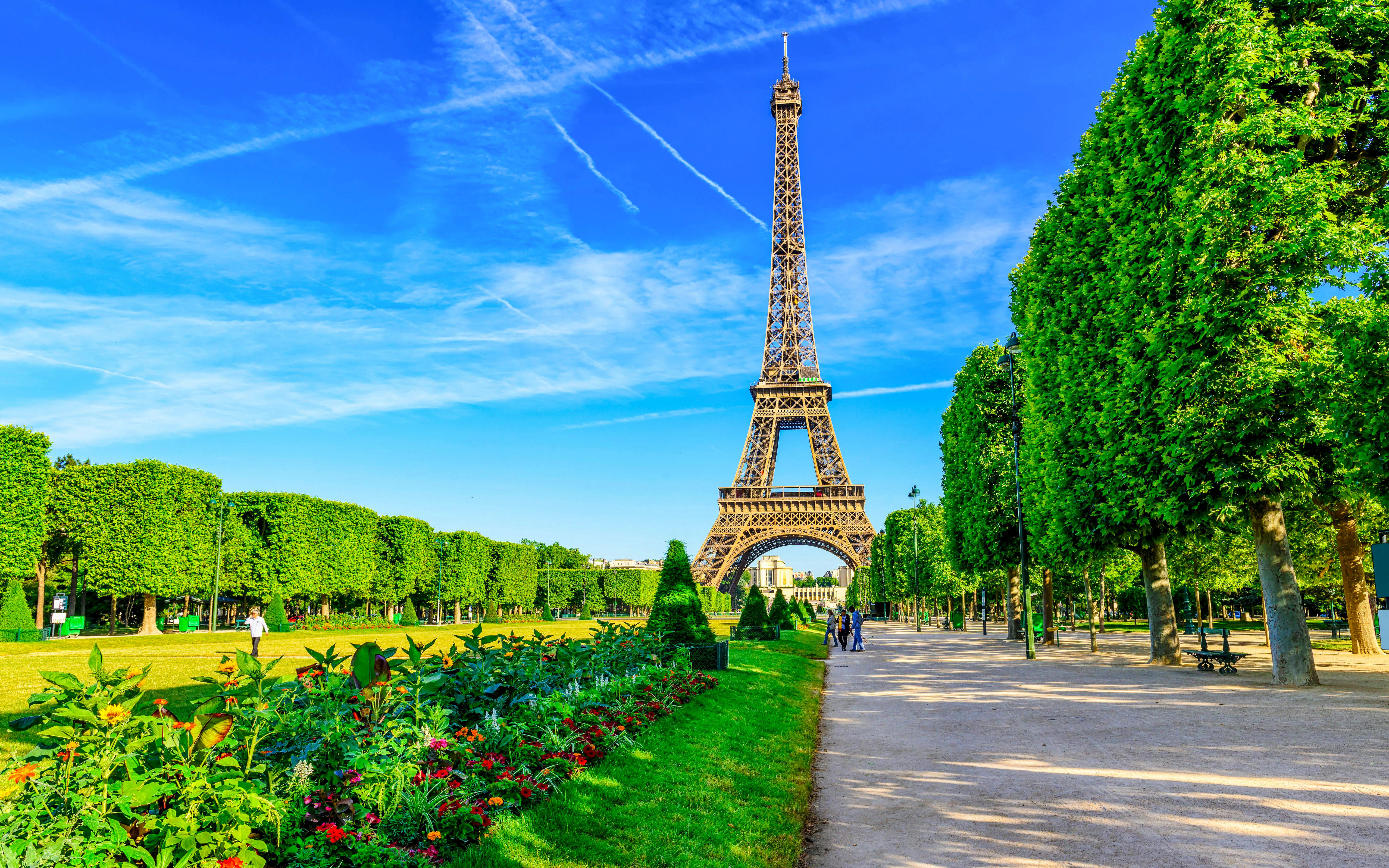 Eiffel Tower viewed from Champ de Mars with gardens and pathway in Paris.