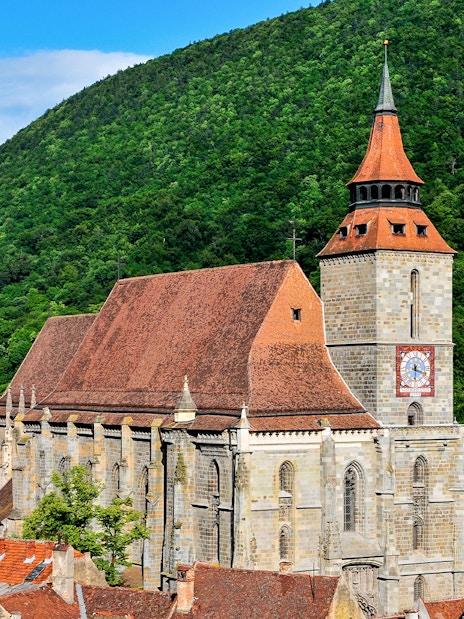 Black Church in Brașov with forested hill backdrop.