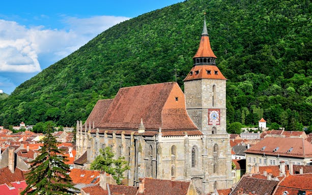 Black Church in Brașov with forested hill backdrop.