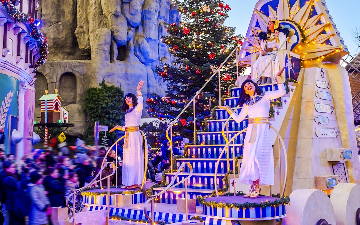 Performers in Egyptian costumes on a festive float at Parc Asterix Christmas celebration.