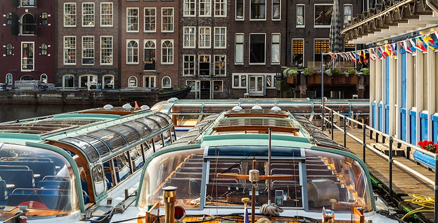 Canal boats docked in front of traditional Amsterdam houses.