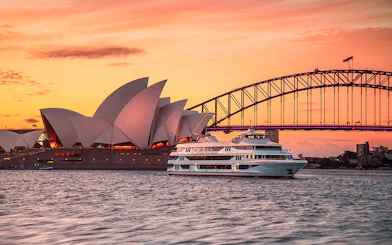 Captain Cook Cruise at sunset near Sydney Opera House and Harbour Bridge.