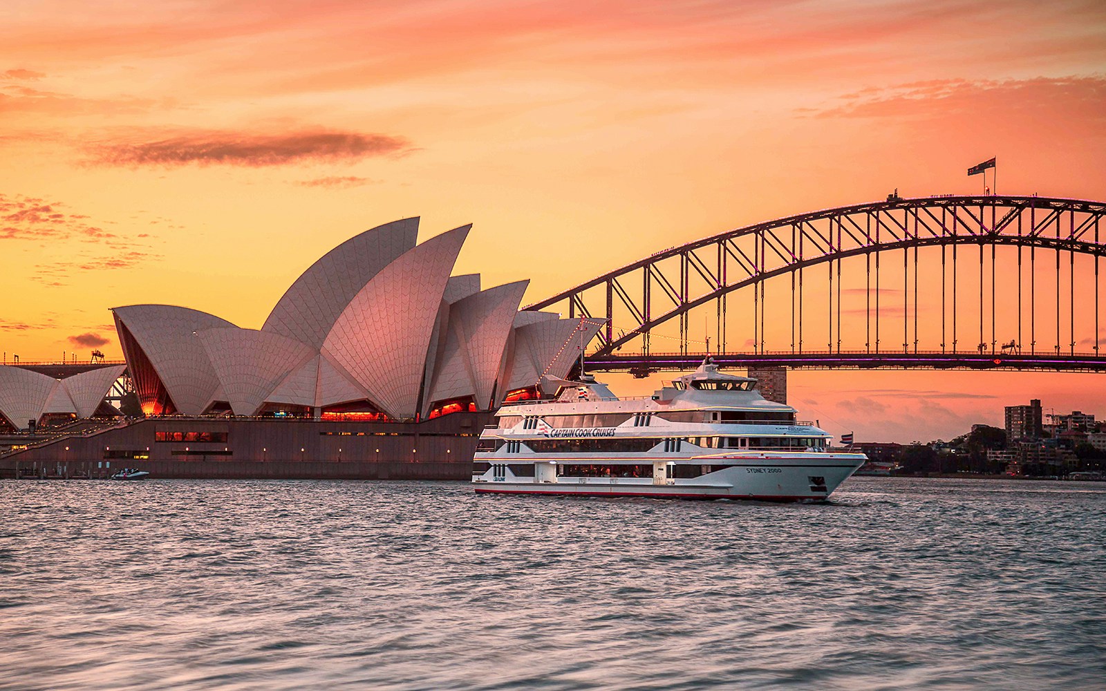 Sydney Harbour view from Captain Cook Cruise at sunset with city skyline and Sydney Opera House.