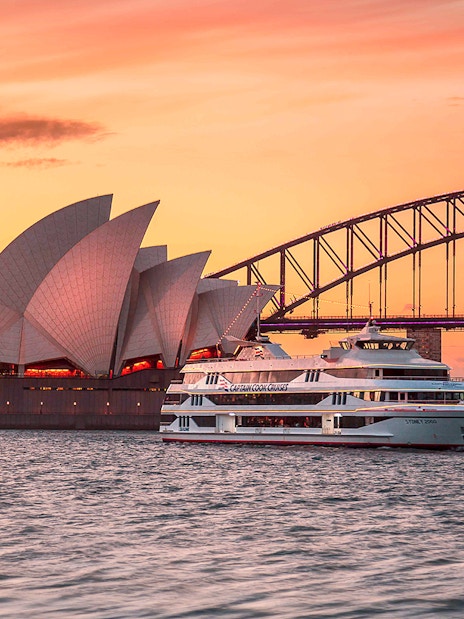 Captain Cook Cruise at sunset near Sydney Opera House and Harbour Bridge.