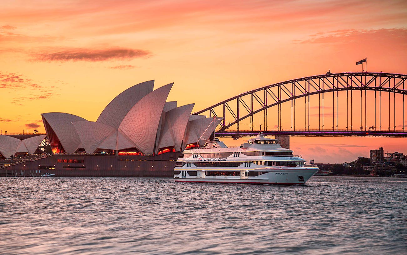 Captain Cook Cruise at sunset near Sydney Opera House and Harbour Bridge.