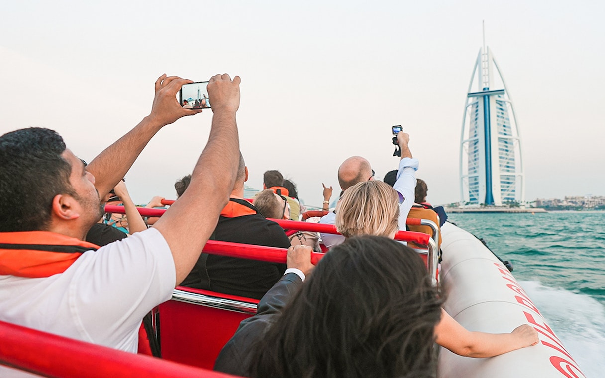 Tourists on a boat capturing the Burj Al Arab in Dubai during a marina tour.