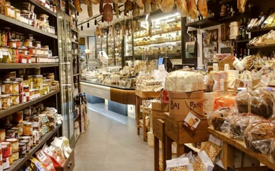 Italian deli with hanging cured meats and shelves of gourmet products, Florence Walking Tour.