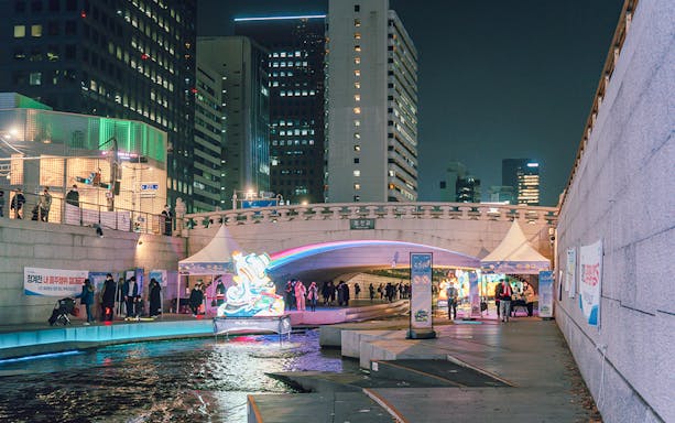 Cheonggyecheon Stream at night with illuminated bridge and cityscape, Seoul Night Guided Tour.
