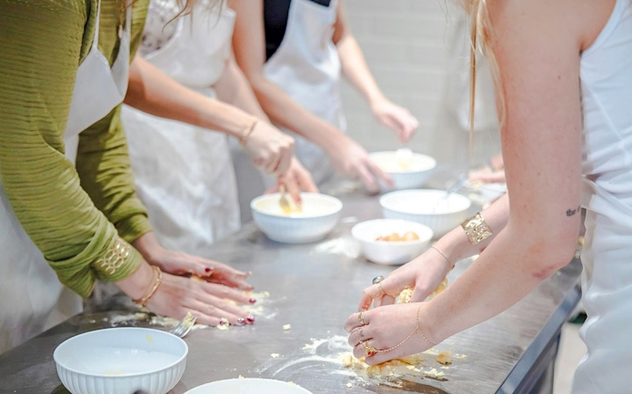 Participants preparing dough in a small group cooking class in Florence.