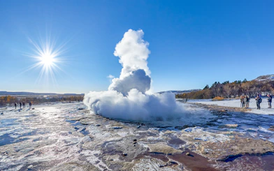 Strokkur Geyser erupting with steam in Iceland's geothermal area under a clear blue sky.