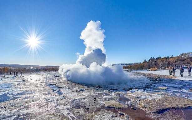 Strokkur Geyser erupting with steam in Iceland's geothermal area under a clear blue sky.