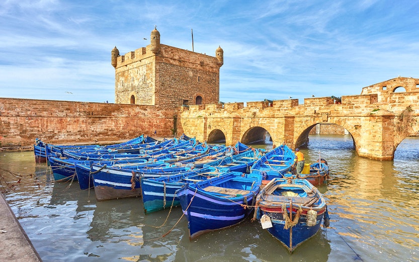 Blue fishing boats docked by the historic Skala de la Ville in Essaouira, Morocco.