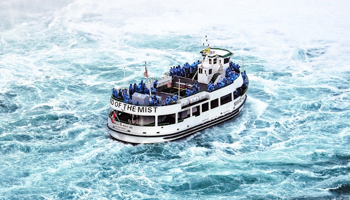 Niagara Falls boat tour with passengers in raincoats approaching the waterfall.