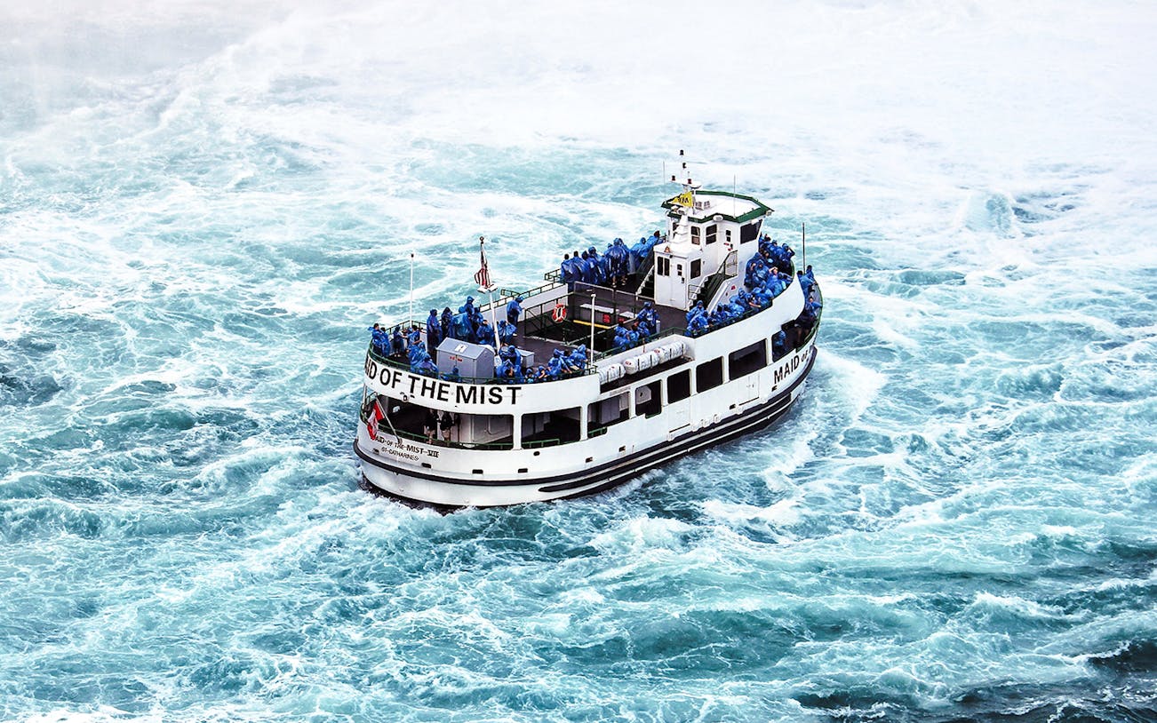 Boat with passengers in raincoats near Niagara Falls.