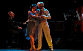Dancers performing at Homero Manzi Tango Show with live musicians in Buenos Aires.