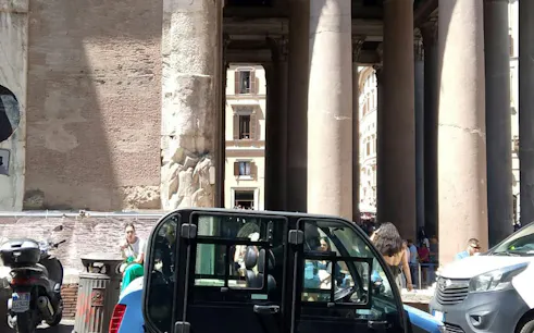 Golf cart parked near ancient columns in Rome city center.