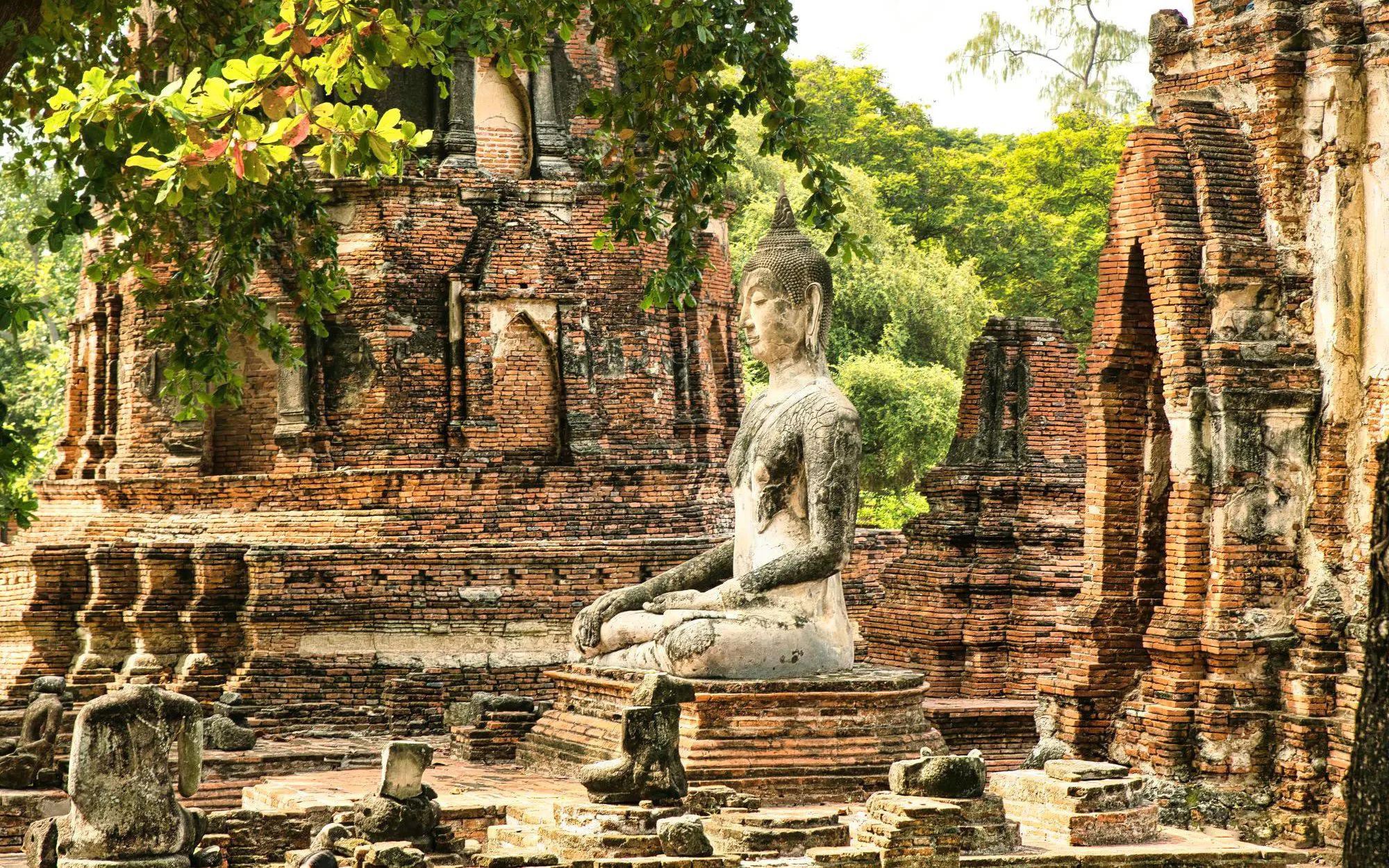 Buddha statue among ancient brick ruins at Wat MahaThat, Ayutthaya, Thailand.