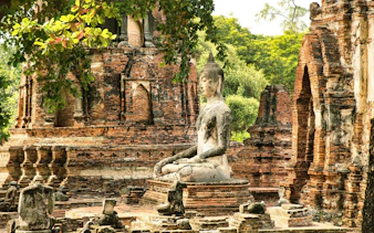 Buddha statue among ancient brick ruins at Wat MahaThat, Ayutthaya, Thailand.