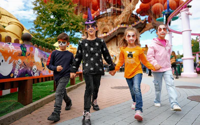 Children in Halloween costumes walking at Gardaland theme park.