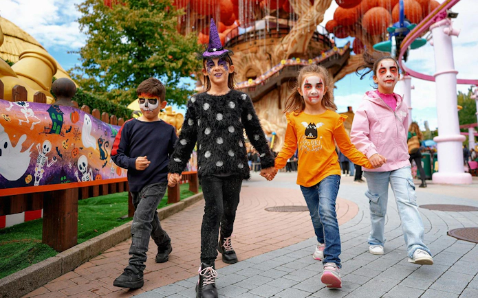 Children in Halloween costumes walking at Gardaland theme park.