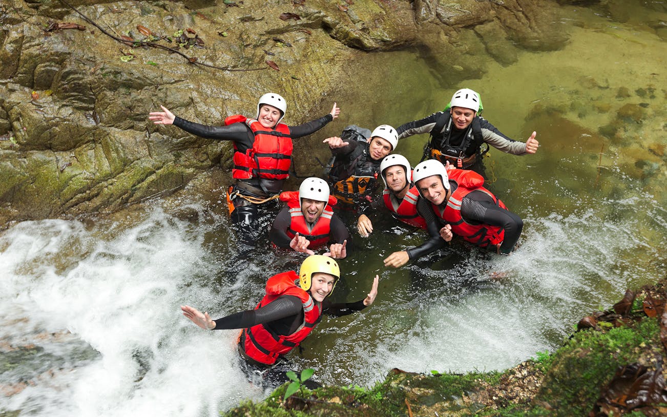 Group enjoying Chli Schliere canyoning in Interlaken, wearing helmets and life vests in a rocky stream.