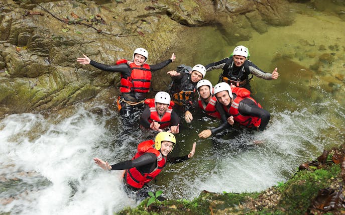 Group enjoying Chli Schliere canyoning in Interlaken, wearing helmets and life vests in a rocky stream.