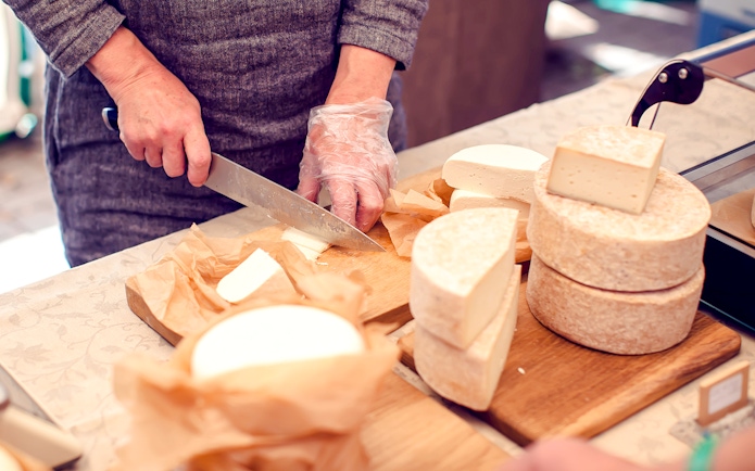 Chef slicing cheese at Cheese Museum in Paris.