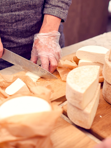 Chef slicing cheese at Cheese Museum in Paris.