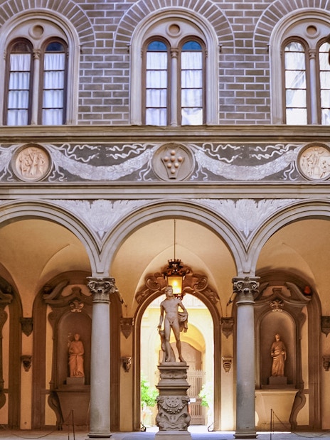 Palazzo Medici Riccardi courtyard with classical statues and ornate arches in Florence, Italy.