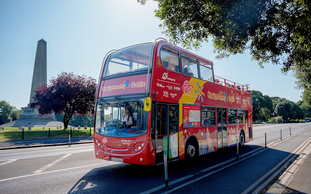 Open-top tour bus in Dublin passing the Wellington Monument in Phoenix Park.