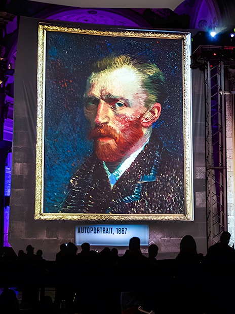 Van Gogh self-portrait displayed at London exhibition with guests viewing.