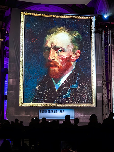 Van Gogh self-portrait displayed at London exhibition with guests viewing.