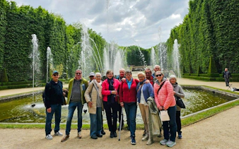 Group enjoying Versailles guided tour by fountains.